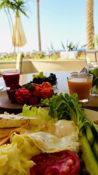 Rich all inclusive breakfast with mango juice, fresh strawberry, salmon and basturma meat on luxury 5-star hotel terrace in Sharm El Sheikh. Lavish chic food styling at resort buffet in Egypt.