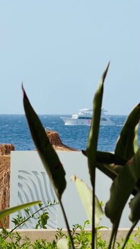 Luxury 5-star hotel resort outdoor terrace with houndstooth chairs and sea view in Sharm El Sheikh. Beautiful white yacht in Red Sea background of premium all inclusive holiday destination in Egypt.