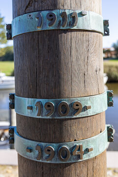 View of the Stormflodssojlen flood column showing historical water levels on weathered metal rings attached to a textured wooden pole Ribe, Denmark.