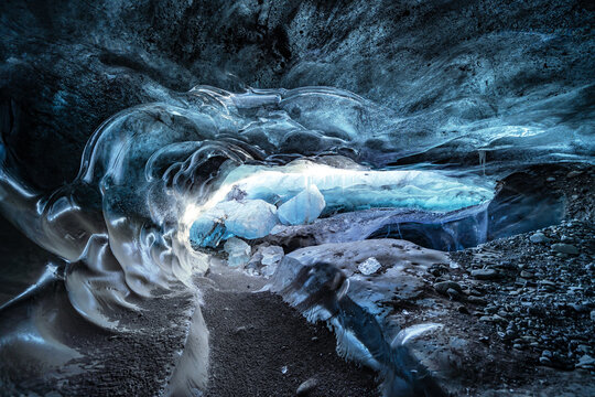 View of the interior of an ice cave with translucent blue ice walls and textured frozen surfaces in Vatnajokull National Park Iceland.