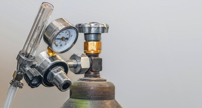 Metal gas cylinder regulator equipped with pressure gauge, valve and transparent flow meter tube.