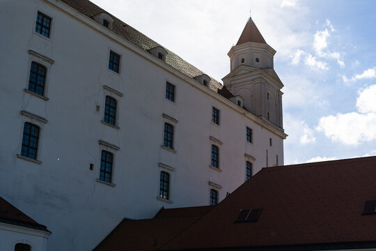 View of the historic Bratislava Castle with its white facade and corner tower under a bright sky in Bratislava, Bratislava Region, Slovakia.