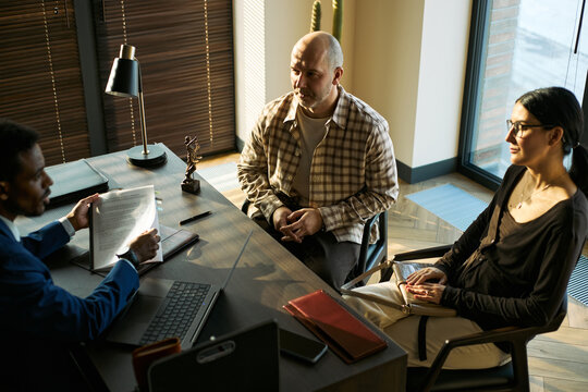 Medium shot of middle aged couple meeting lawyer, reviewing documents during divorce consultation and legal separation process. Useful for family law, custody, mediation marketing