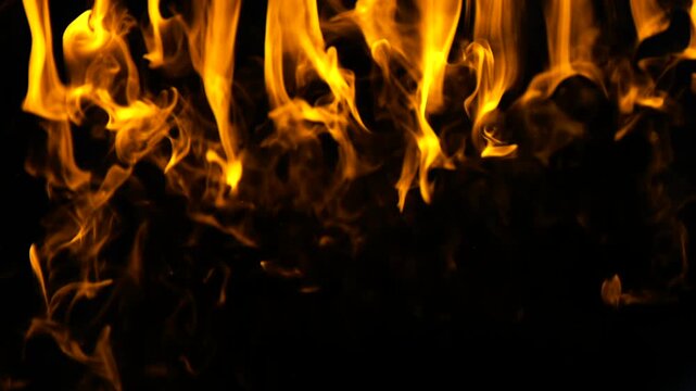 Intense orange and yellow flames burning and flickering against a dark night background. Fiery element creating a hot and infernal atmosphere, perfect for dramatic or abstract concepts