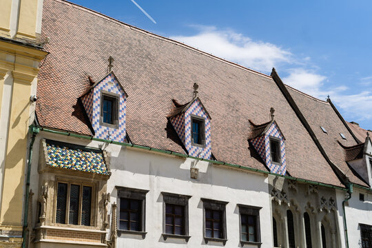 View of the historic Old Town Hall featuring colorful tiled roofs and decorative dormer windows under a clear blue sky in Bratislava, Bratislava Region, Slovakia.