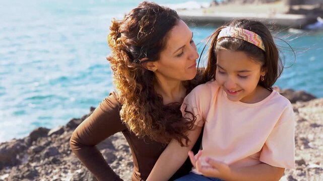 Happy latin mother having fun with daughter on the beach - Mom and female child having tender moment outdoor - Family, love and bonding concept
