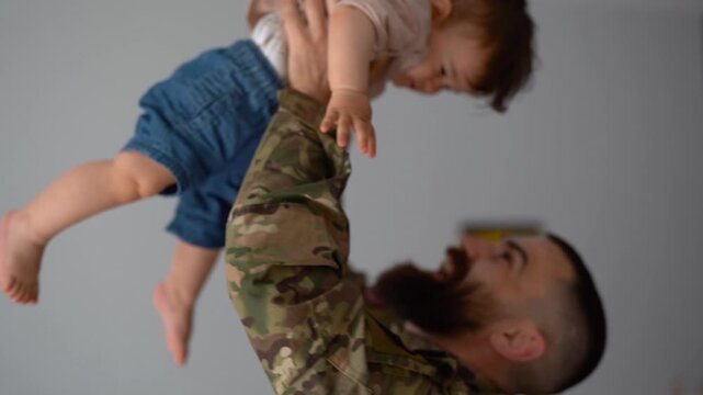 American male soldier in military uniform returning home to family - Father hugging and kissing baby son - Homecoming, happiness and love concept