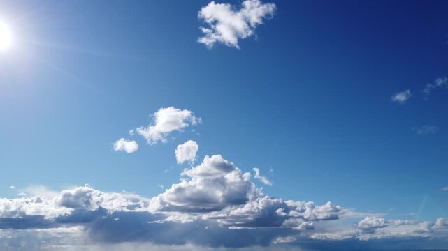Cinematic aerial view of bright sun and white fluffy clouds in a vibrant blue sky, beautiful cloudscape background for transition and copy space, drone flight through clear atmosphere on a sunny day, 