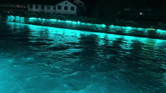 Mesmerizing emerald green lights illuminate the rushing water of the Min River at night in Dujiangyan China creating a futuristic aesthetic.