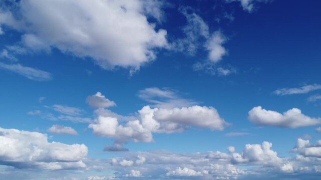 Aerial wide angle view of beautiful white cumulus clouds moving through a vibrant blue sky, cinematic cloudscape background on a bright sunny day, peaceful atmosphere and fluffy clouds