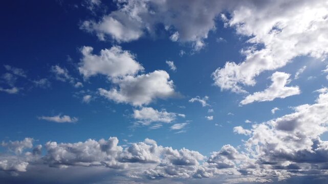 Aerial wide angle shot of a vibrant blue sky filled with white cumulus clouds and bright sunlight, cinematic drone view of a vast cloudscape moving through the atmosphere, high altitude 