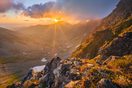 View of Smutne sedlo in Western Tatras during a golden sunset with a sunburst over rugged mountain peaks and rocky slopes Ziar, Zilina Region, Slovakia.