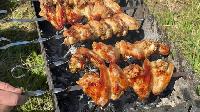 Chicken satay is grilled over an open fire with hot coals and smoke coming out .