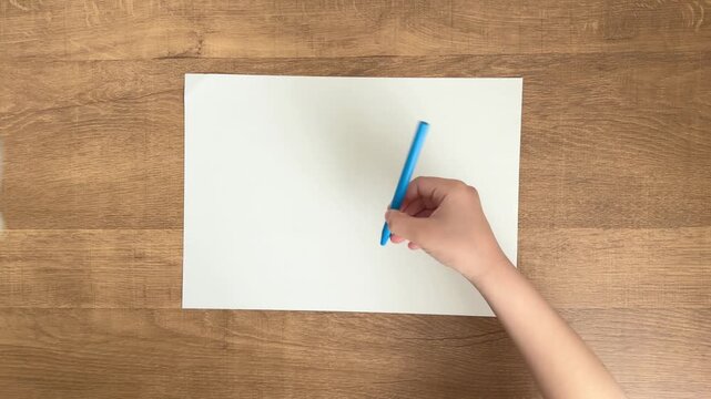 child hands picking up light blue pen from white paper slow motion 4K