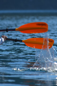 View of orange kayak paddles splashing into the clear blue waters of Nahuel Huapi Lake San Carlos de Bariloche, Rio Negro, Argentina.