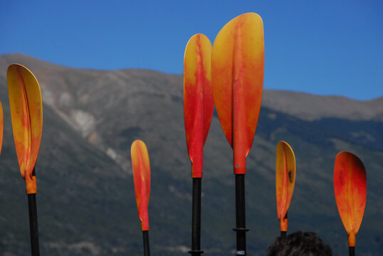 View of orange and yellow kayak paddles standing upright with the mountains and Nahuel Huapi Lake in the background SAN CARLOS DE BARILOCHE, Rio Negro, Argentina.