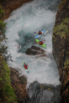 View of kayakers navigating the white water rapids of Rio Manso through a narrow rocky canyon with lush vegetation San Carlos de Bariloche, Rio Negro, Argentina.