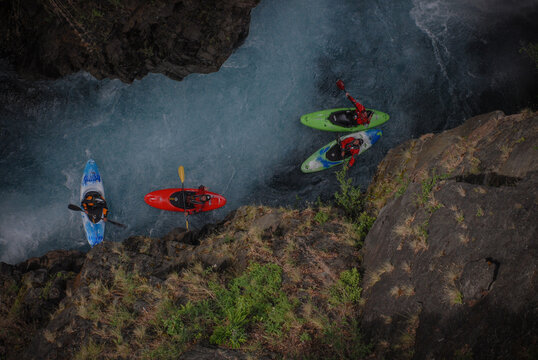 View of kayakers paddling through the turquoise waters of the Rio Manso canyon surrounded by steep rocky cliffs and lush vegetation San Carlos de Bariloche, Rio Negro, Argentina.