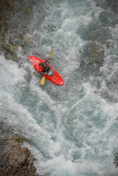 View of a person in a red kayak navigating through the white-water rapids of the Rio Manso amidst churning turquoise water San Carlos de Bariloche, Rio Negro, Argentina.