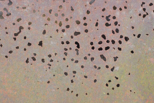 brown metal texture of rusty iron wall with a row of round holes