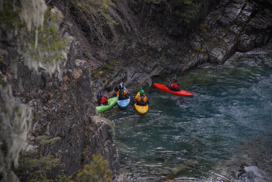 View of kayakers paddling through the turquoise waters of the Rio Manso canyon surrounded by rugged rocky cliffs and lush forest San Carlos de Bariloche, Rio Negro, Argentina.