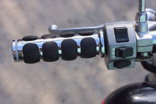part of a old motorcycle with black gray steering wheel on the summer street