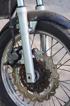 one gray black wheel on a motorcycle fork on a gray background on a summer city street