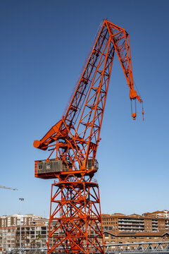 View of the historic red Carola Crane standing tall against a clear blue sky with urban buildings in the background Greater Bilbao, Basque Country, Spain.
