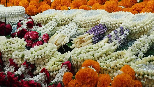 Traditional Phuang Malai flower garlands lying at market stall, jasmine Jasminum sambac and marigold Tagetes arrangements, Thai religious offering and cultural festival decoration