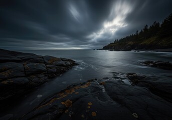 Fototapeta premium A moody, tranquil coastal landscape featuring dark water washing onto a rugged shore beneath an expansive, overcast sky ,coast ,shore ,landscape