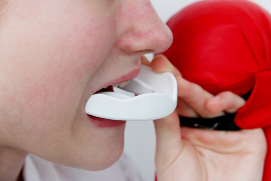 Close-up of boxer wearing mouthguard and red boxing gloves, representing combat sports, protection, training, and martial arts safety concep