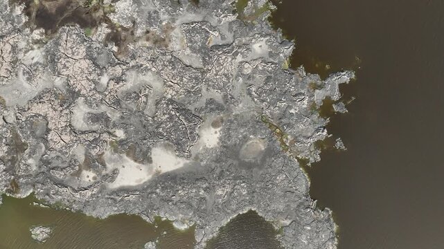 Aerial view of the Danakil Desert showing cracked mineral deposits and dark geothermal pools in the volcanic landscape of Dalol, Afar, Ethiopia.