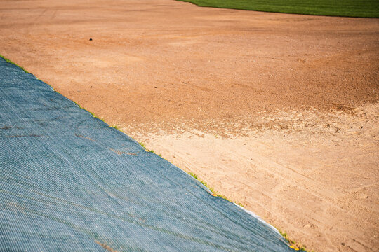 Municipal works for summer seasonal grass lawn preparation in city parks and gardens, part of ground covered with special protective net to prevent seeds damage, landscape development in urban town.