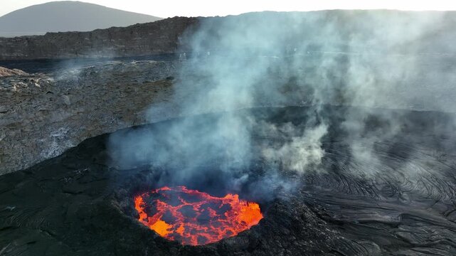 Aerial view of the glowing lava lake of Erta Ale volcano with thick smoke rising from the crater in the Danakil Desert, Dalol, Afar, Ethiopia.
