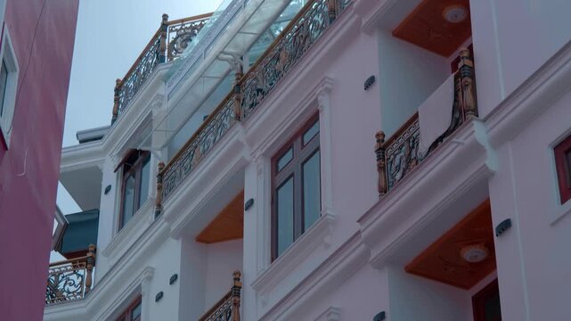 A decorative wrought-iron or cast-iron swing gate with a decorative panel with coat of arms depicting a lion and a horse are the entrance to a colonial modern style building with carved balconies and 