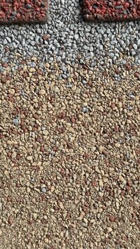Close-up cottage roof tiles showing granular texture, rough mineral granules, dark vertical seam lines, offset tile arrangement
