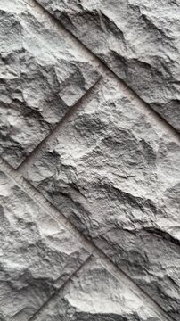 Close-up textured stone facade panels, dark brown natural stone with chiseled rough surface, modular block layout with visible