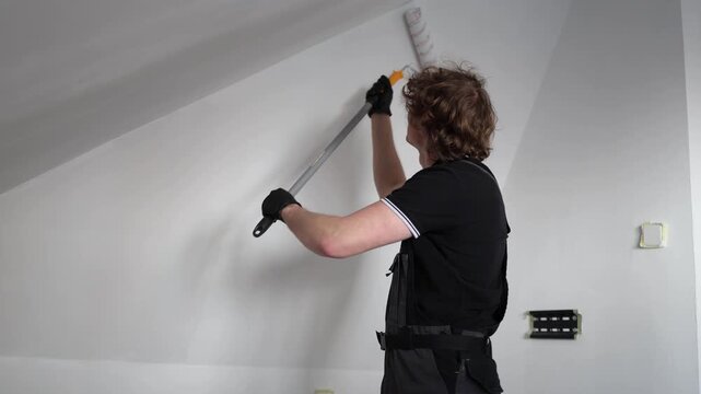 Young homeowner repainting apartment walls during expensive renovation project trying to refresh living space despite rising repair and construction costs