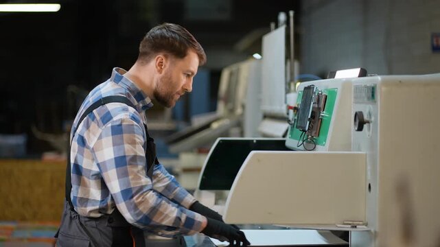 Print plant operator adjusting industrial printing machine