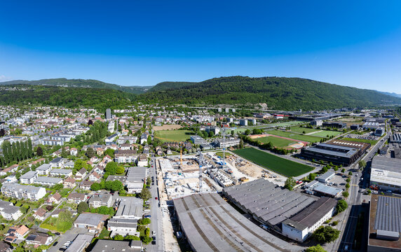 Aerial view of the Biel Bienne Boezingenfeld Champ industrial area with a construction site, cranes, and residential buildings under a clear blue sky Biel Bienne, Canton of Bern, Switzerland.