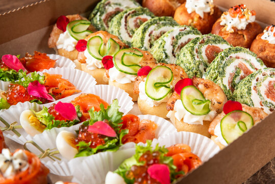 A gourmet selection of catering appetizers and canapes with salmon, cream cheese, and caviar in a box.