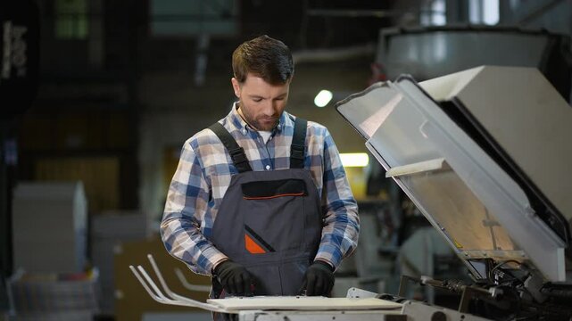 Print plant operator working at industrial printing machine