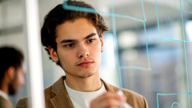 gen z entrepreneurgen concept. Focused individual brainstorming ideas on a transparent board in a modern workspace.