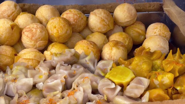 Close up of freshly cooked takoyaki balls and assorted steamed dim sum in a food stall steamer