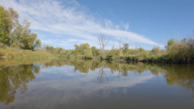 POV view from the front of a canoe paddling on a quiet northern river in the fall
