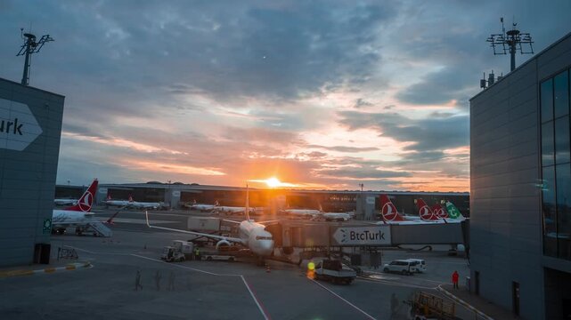 Timelapse at Istanbul Airport at sunrise shows Turkish Airlines jets at gates, a BtcTurk jetbridge on a narrow body, ground crews and vehicles, and shifting clouds.