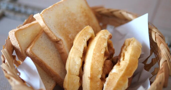 Cinematic close-up of crispy toasted white bread and fresh waffles in a wicker basket, morning bakery and breakfast buffet concept