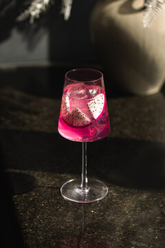 Tropical dragon fruit drink with ice cubes served in elegant glass under dramatic natural light