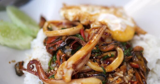 Cinematic close-up of traditional Thai stir-fried seafood with holy basil (Pad Kra Prow Talay) served over steamed rice with a crispy fried egg