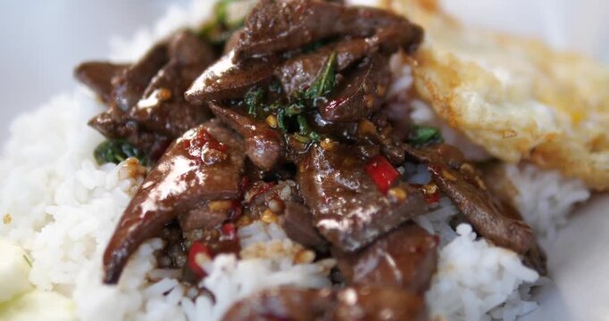 Cinematic close-up of traditional Thai stir-fried pork liver with holy basil (Pad Kra Prow Tap) served over jasmine rice with a fried egg
